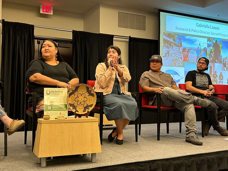 A close-up photo of a panel discussion with panelists seated on the stage with a presentation on display behind them